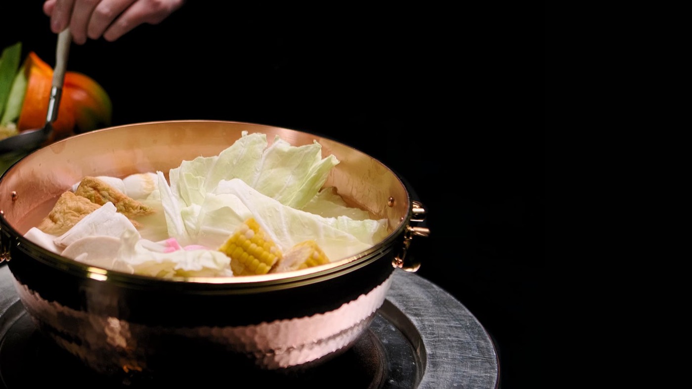 橘色銅鍋涮煮高麗菜與玉米筍