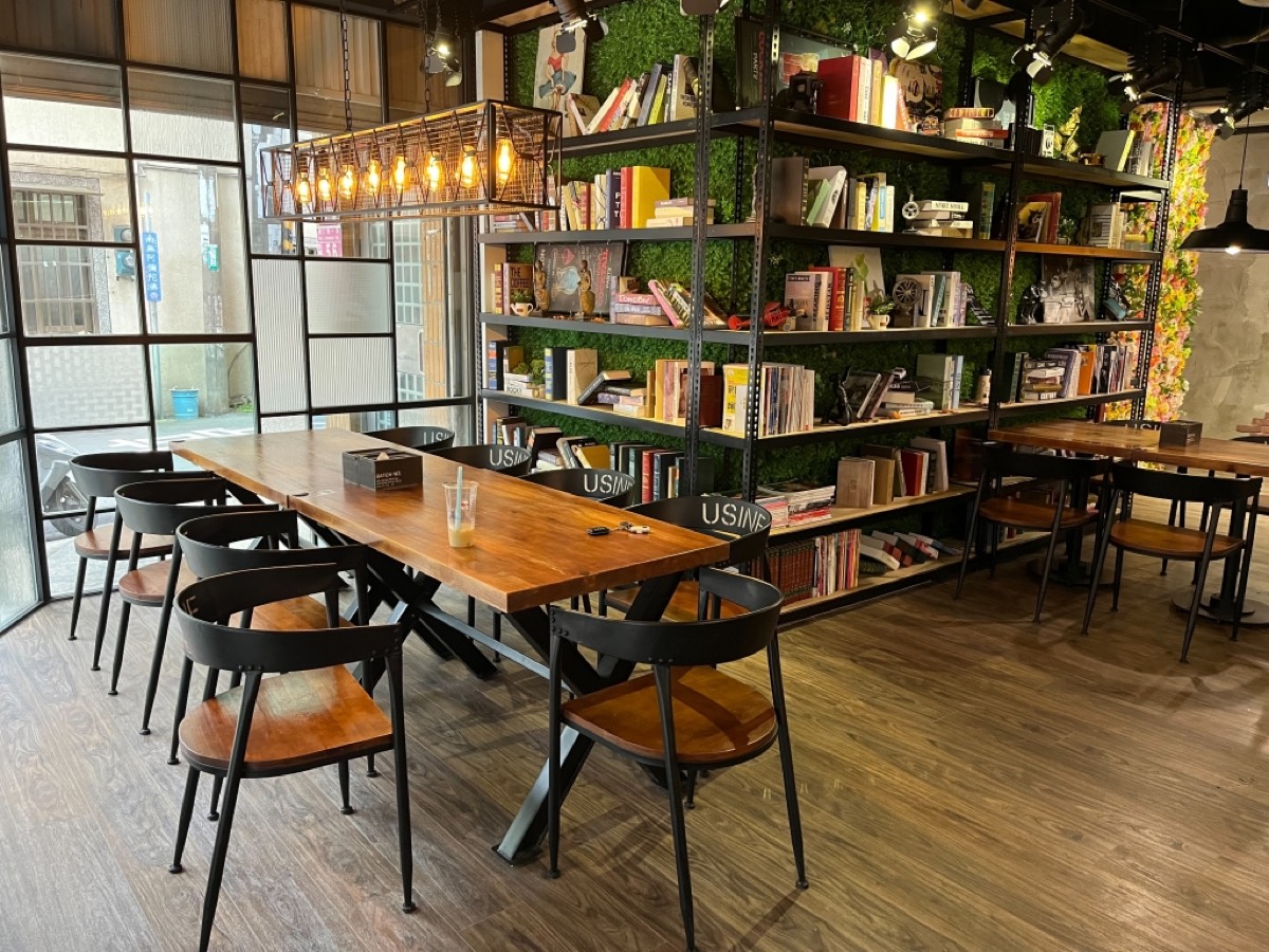 書店咖啡廳木地板案場，長桌與整面書牆、吊燈